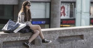 ragazza su un muretto con una shopping bag
